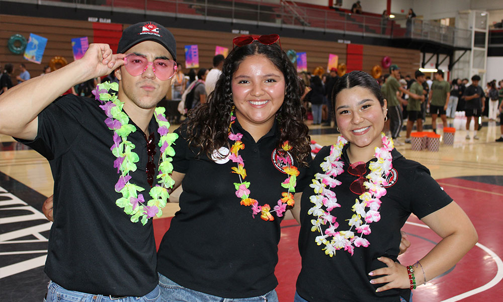 Two Imperial Valley College students stand on campus holding an Imperial Valley College banner, smiling for the camera.